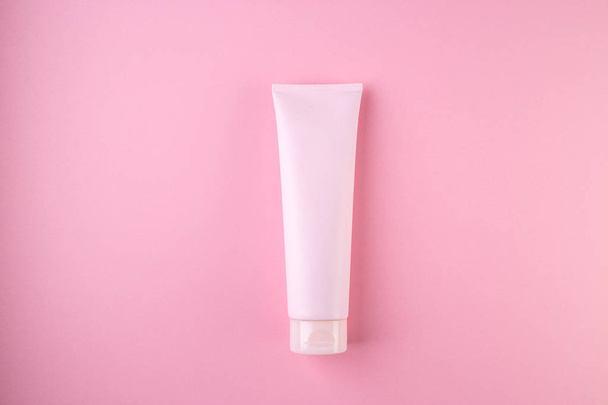 Plastic tube with face or body cream on pastel pink background - Fotó, kép