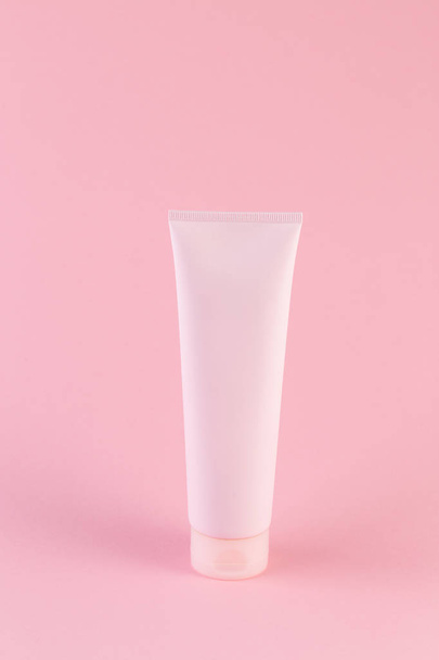 Plastová trubice s obličejem nebo tělesnou smetanou na pastelově růžovém pozadí - Fotografie, Obrázek