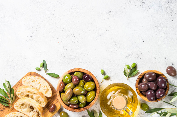 Olijven, ciabatta en olijfolie op witte achtergrond. - Foto, afbeelding