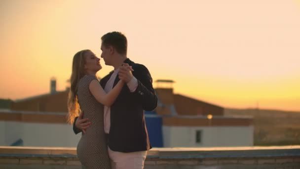 Two lovers embracing dancing on top of a skyscraper overlooking the city at sunrise sunset. Romantic setting. - Záběry, video