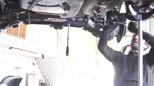 auto mechanic repairing automobile against intensive light. - Footage, Video