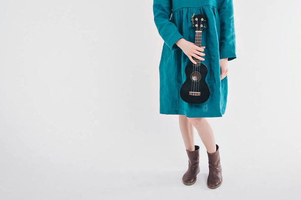 beautiful girl in blue dress with small guitar in hands on white background. The concept of advertising musical instruments, fashion, symbols - Φωτογραφία, εικόνα