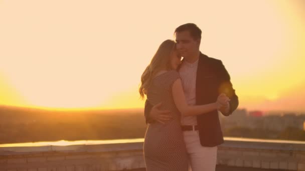 Két szerelmes felölelő tánc tetején egy felhőkarcoló, kilátással a városra napkelte naplemente. Romantikus alapbeállítás. - Felvétel, videó