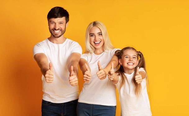 Famiglia gesturing Pollici-Up in piedi su sfondo giallo
 - Foto, immagini