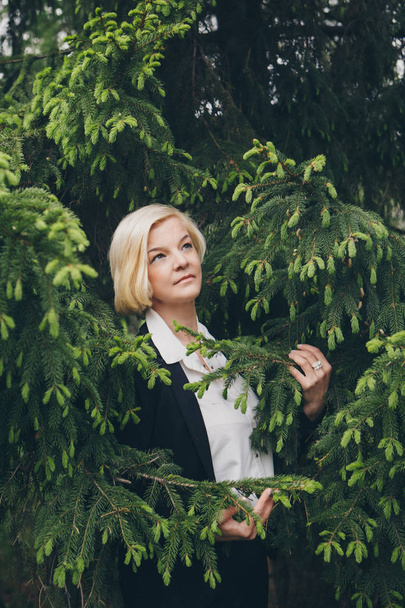 the concept of working on the street, day rest - a Fashionable stylish portrait of a woman with white short hair. businesswoman walking in the Park among the trees. - Фото, зображення