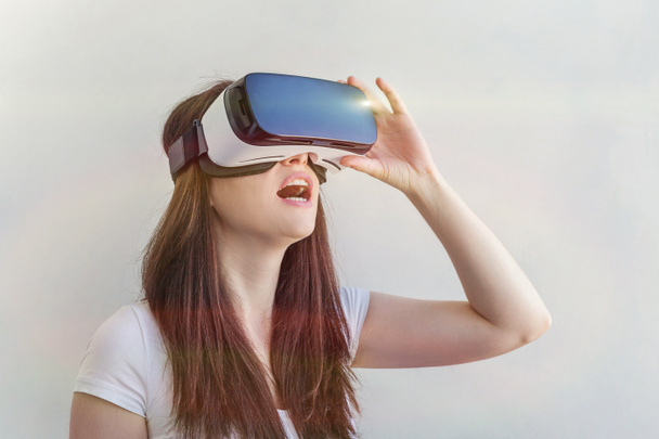 Sorria jovem vestindo usando realidade virtual óculos VR capacete headset no fundo branco
 - Foto, Imagem