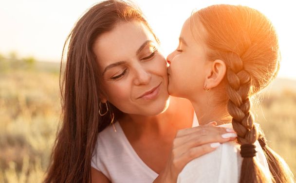 Girl kissing mother in field - Photo, image