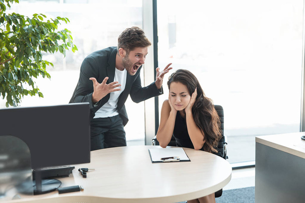strict boss man swearing at depressed employee woman for bad work at the workplace looking angry - Photo, Image