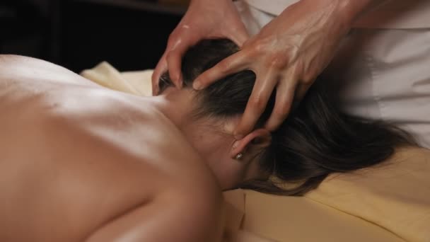 Female lying on massage table at spa salon. Male masseur doing neck and head massage for attractive young woman. Brunette enjoying massage in slow motion. 4k, UHD - Metraje, vídeo