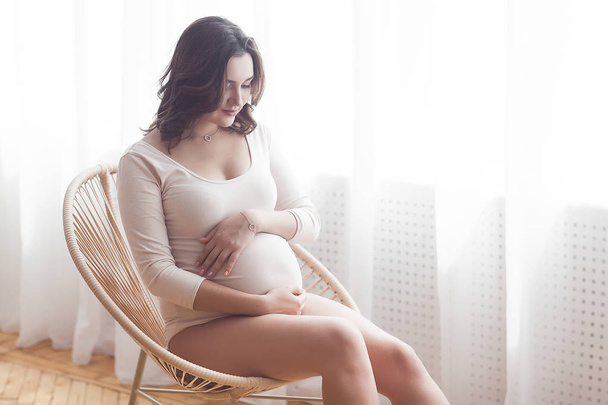 Όμορφη έγκυο γυναίκα σε ουδέτερο φόντο. Μέλλουσα φωτογραφία. Μελλοντική μητέρα πορτρέτο σε παστέλ φόντο. - Φωτογραφία, εικόνα