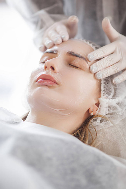 meester maakt een cosmetische ingreep voor haar cliënt. huidverzorging. vrouw maken van een gezichtsverzorging procedure. - Foto, afbeelding