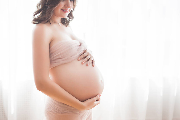 Piękna kobieta w ciąży na neutralnym tle. Spodziewany zbliżenie obrazu. Przyszły portret matki na tle pastelowych. - Zdjęcie, obraz