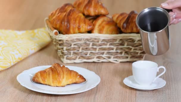 Cup of fresh coffee with croissants on wooden background. Pouring espresso into a cup - Footage, Video