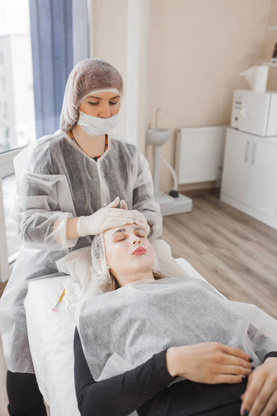 Master haciendo un procedimiento cosmético para su cliente. Tratamiento de la piel. mujer que realiza un procedimiento de atención facial. - Foto, imagen