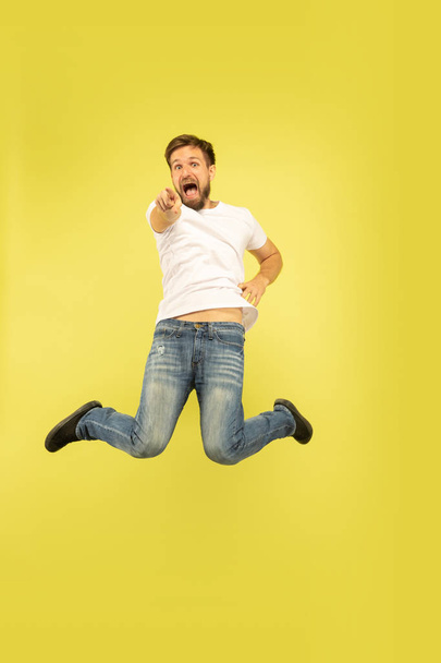 Full length portrait of happy jumping man on yellow background - Photo, image