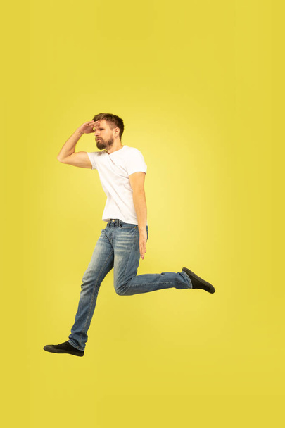Full length portrait of happy jumping man on yellow background - Fotoğraf, Görsel