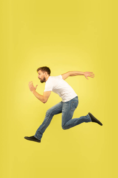 Full length portrait of happy jumping man on yellow background - Фото, зображення