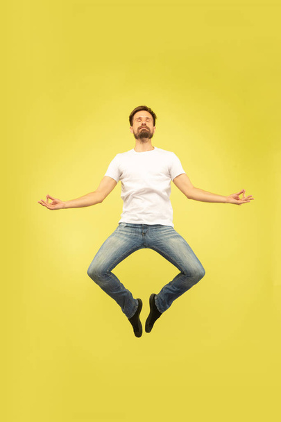 Full length portrait of happy jumping man on yellow background - Foto, imagen