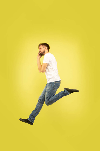 Full length portrait of happy jumping man on yellow background - Фото, изображение
