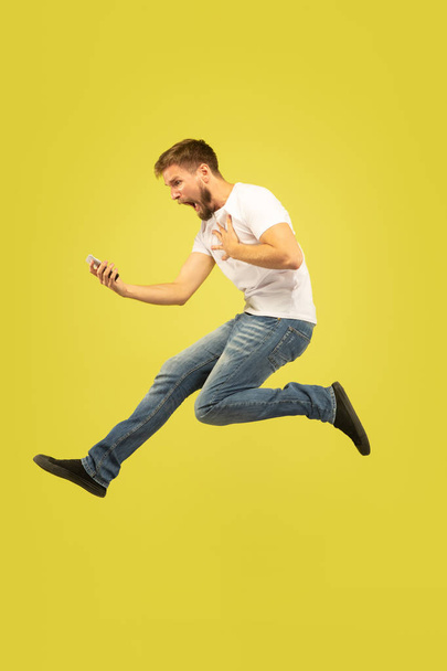 Full length portrait of happy jumping man on yellow background - Foto, imagen