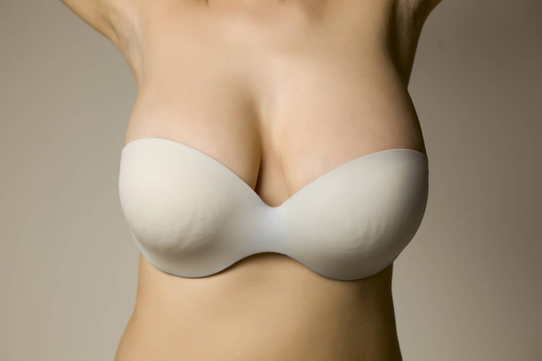 Beautiful big breasts in bra on gray background - Photo, Image