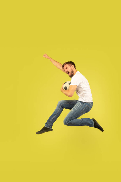 Full length portrait of happy jumping man on yellow background - Fotó, kép