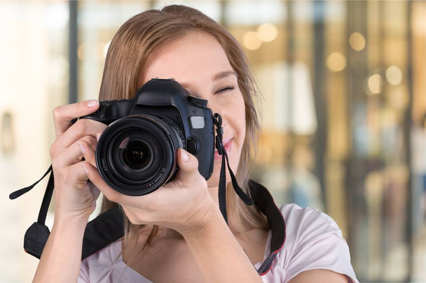 Молода жінка-фотограф з камерою в студії
 - Фото, зображення