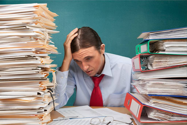 Homme d'affaires fatigué au bureau avec pile de documents
  - Photo, image