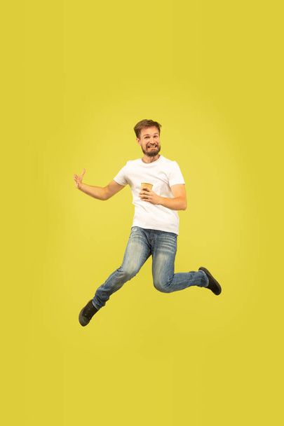 Full length portrait of happy jumping man on yellow background - Valokuva, kuva