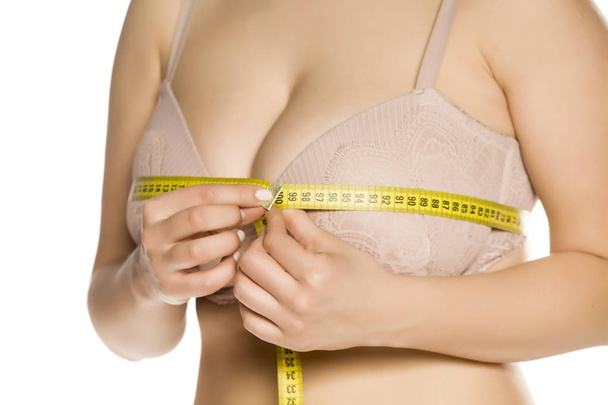 Mujer medir sus enormes pechos con cinta métrica sobre fondo blanco
 - Foto, Imagen