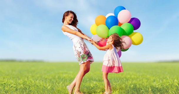 mother with daughter holding colorful balloons - Photo, Image
