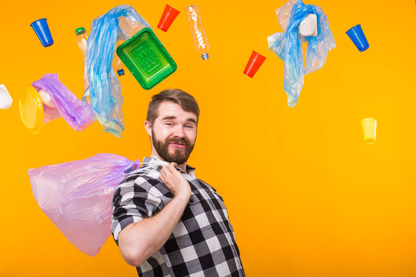 Znečištění životního prostředí, problém recyklace plastů a koncepce likvidace odpadu-zábavný muž držící popelnici na žlutém pozadí. - Fotografie, Obrázek
