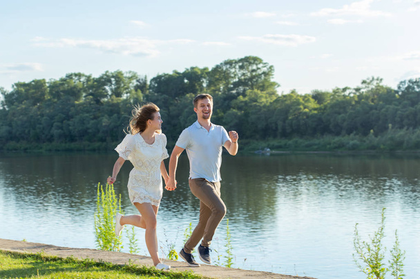 Letní příroda, vztahy a lidé v milostné koncepci-šťastný pár, který běží blízko jezera - Fotografie, Obrázek