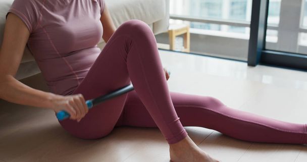 Woman use of roller stick on thigh to release pain at home - Valokuva, kuva