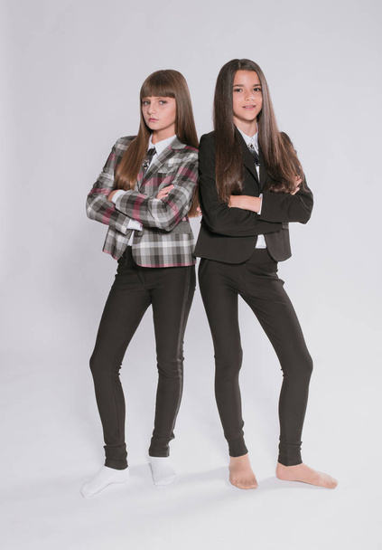Two cute girls schoolgirls in a trendy school uniform on a white background. School fashion. Children's school fashion clothes - Zdjęcie, obraz