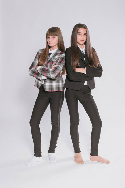 Two cute girls schoolgirls in a trendy school uniform on a white background. School fashion. Children's school fashion clothes - 写真・画像