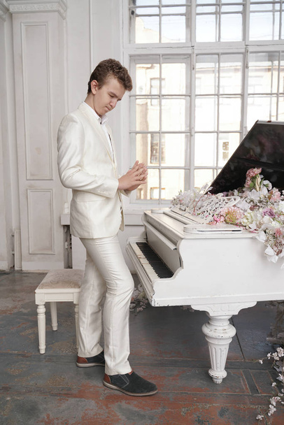 young teenager man with white big grand piano indoors alone enjoys music - Foto, imagen