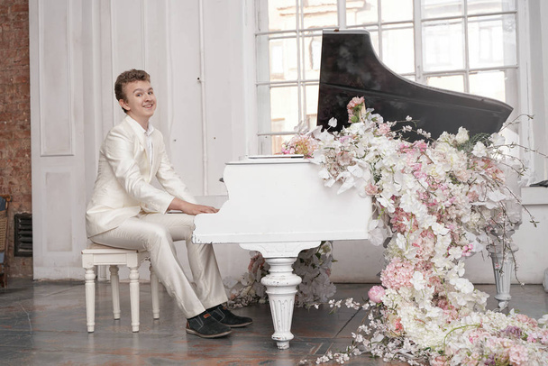 молодий підліток чоловік з білим великим грандіозним піаніно в самоті насолоджується музикою
 - Фото, зображення