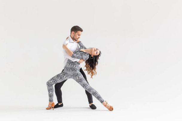 Концепция социального танца - активные счастливые взрослые танцуют бачата вместе на белом фоне с копировальным пространством
 - Фото, изображение