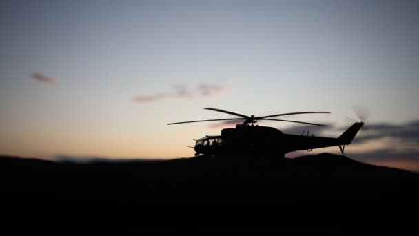 Silhouette of military helicopter ready to fly from conflict zone. Decorated night footage with helicopter starting in desert with foggy toned backlit. Selective focus. - Footage, Video
