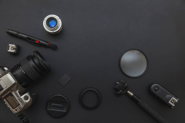 Fotograaf werkplek met DSLR camera systeem, camera reiniging kit, lens en camera accessoire op donkere zwarte tafel achtergrond - Foto, afbeelding