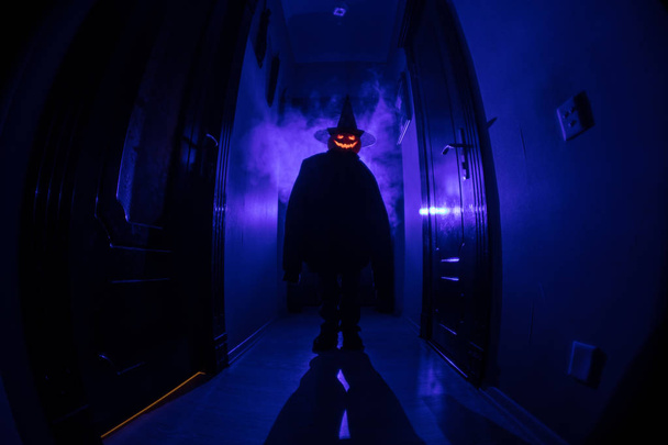 Halloween-Konzept. Gruselige Silhouette im dunklen Gang mit Kürbiskopf. getöntes Licht mit Nebel auf dem Hintergrund. Selektiver Fokus - Foto, Bild