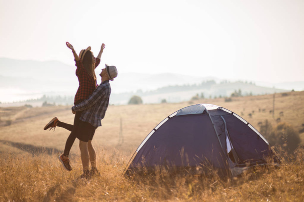 Φιγούρα του στοργικό ζευγάρι ταξιδεύουν Χαλαρώστε camping στις φθινοπωρινές διακοπές. Στην κορυφή του Μουσείου. Απολαύστε την ανατολή του ηλίου μαζί με τα χέρια ψηλά. - Φωτογραφία, εικόνα