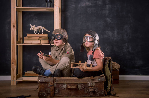 Chlapec si hraje na pilota. Ročník retro dětský portrét v brýlích sedící na starém kufříku s dalekohledem a kompasem v rukou. Inovace, cestování a vyšetřování. - Fotografie, Obrázek