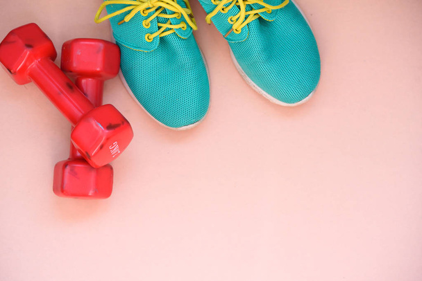Red dumbbells and blue sports sneakers on a light background - Photo, image