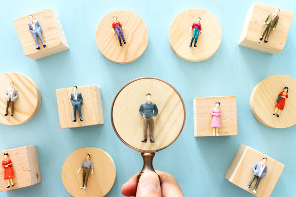 Business image of magnifying glass with people figures over blue background, building a strong team, human resources and management concept - Fotó, kép