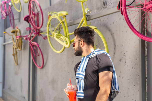 Portrait of a stylish young hipster arab male with juice. Urban holiday at the weekend concept. - Photo, Image