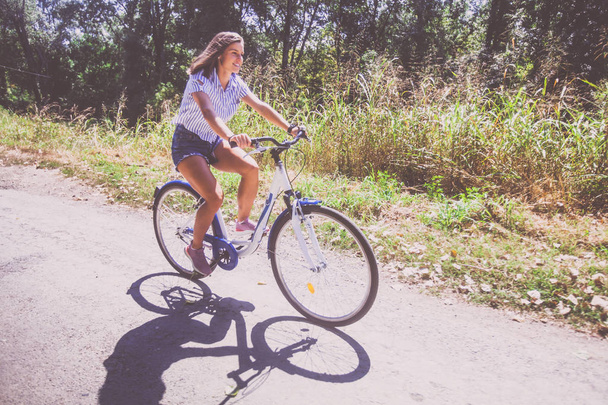 Красивая молодая женщина на велосипеде в парке
  - Фото, изображение