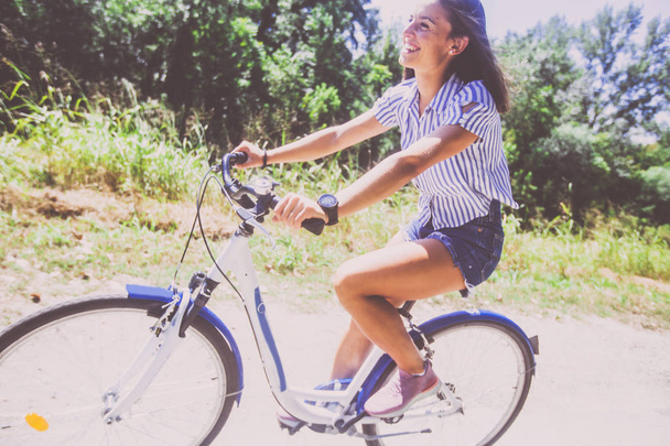 Pretty Young Woman Riding Bicycle In The Park  - 写真・画像