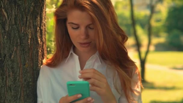 portrait adult woman using smartphone in park - Filmati, video